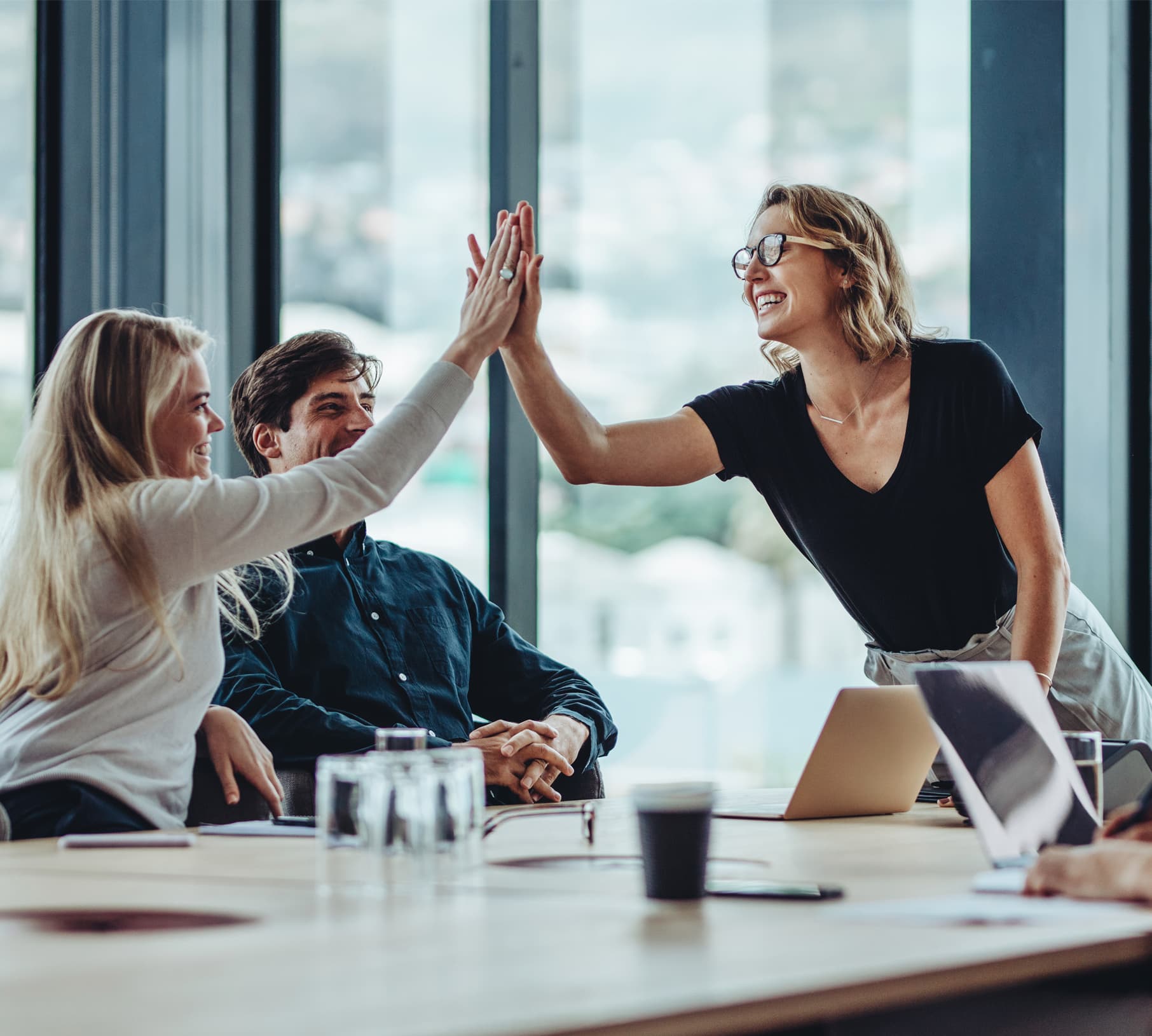 Cost Cures team members celebrating a high five in a meeting room